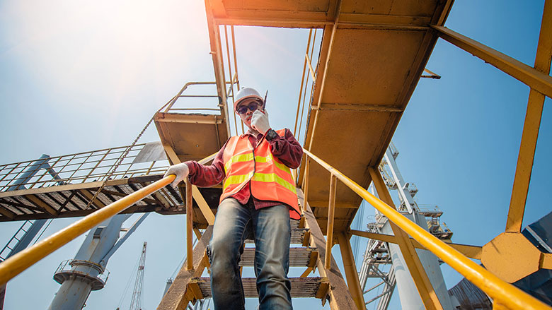 Trabalhador usando capacete, luvas e óculos de proteção durante atividade industrial