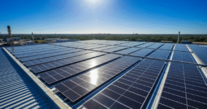 Painéis solares fotovoltaicos instalados em um telhado metálico de uma indústria em Manaus, com vista lateral e superior. O céu está azul e o sol reflete nos módulos, mostrando a eficiência energética.