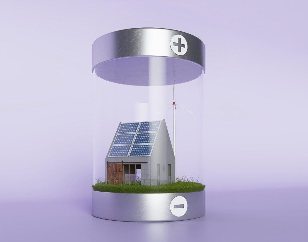 Ilustração 3D de uma bateria gigante e transparente contendo uma casa com painéis solares no telhado e uma turbina eólica ao fundo sobre um gramado verde. O conceito visual representa o armazenamento de energia renovável dentro de uma célula de bateria com polos positivo e negativo.
