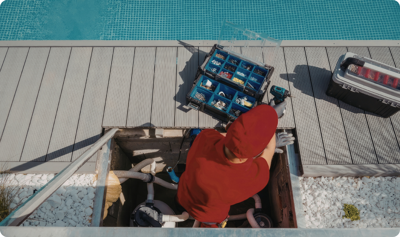 Técnico em manutenção realizando o reparo e instalação de uma bomba de piscina em Manaus, utilizando ferramentas profissionais e organizadores em um deck à beira d'água.