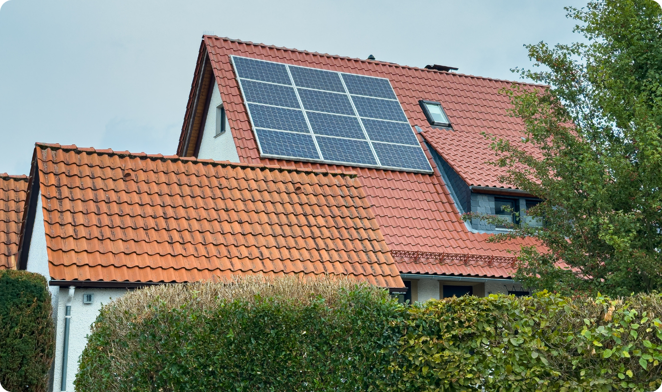 Telhado residencial de telhas cerâmicas laranjas com um conjunto de painéis solares instalados, simbolizando o conforto e a valorização de imóveis com energia solar em Manaus.