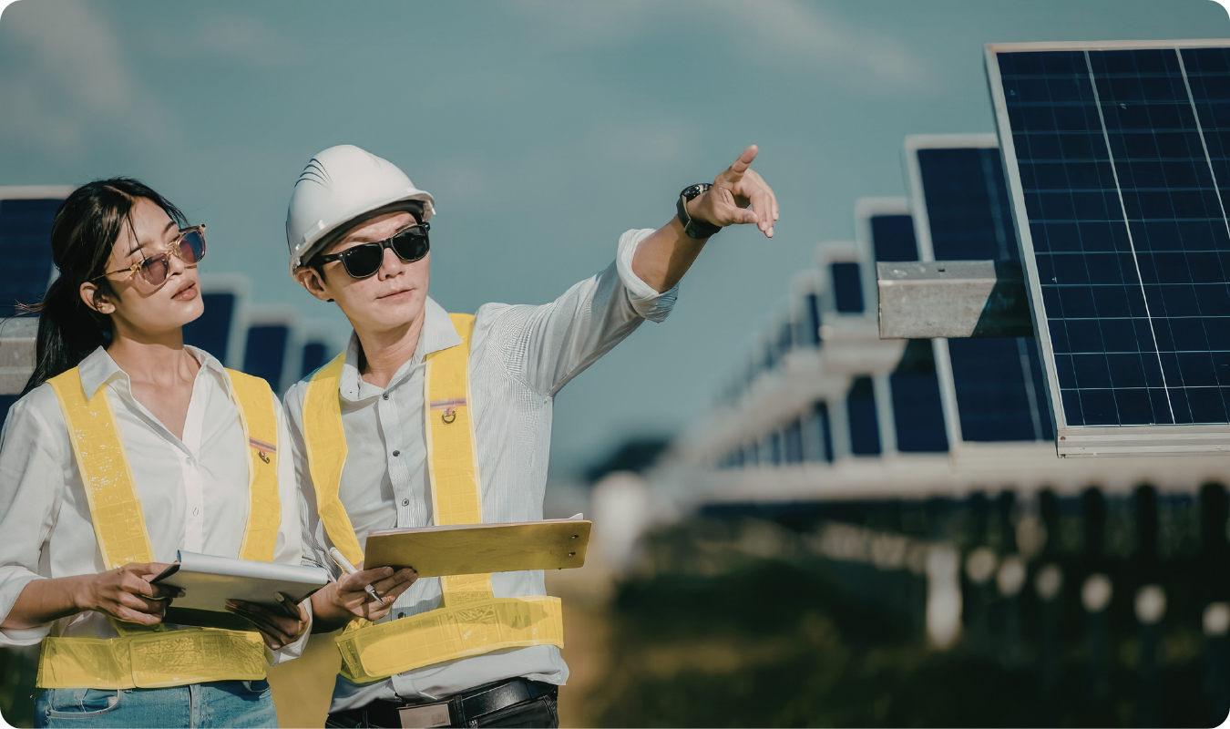 Dois consultores técnicos de colete e capacete analisando uma usina de energia solar em Manaus, apontando para os painéis fotovoltaicos e discutindo o retorno financeiro do projeto.
